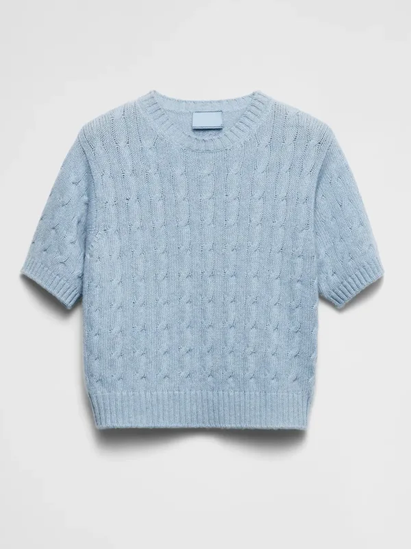 Light blue cable-knit short-sleeve sweater laid flat on white