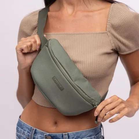 Woman in a beige ribbed crop top wearing a green belt bag